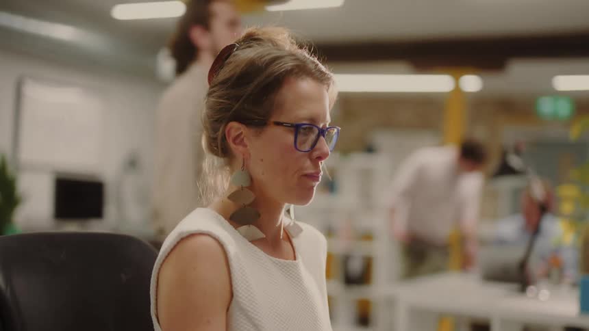 A woman is working and a man is walking beside her and two men are taking behind