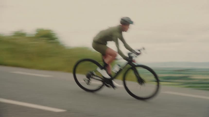 Female cyclist rides along a highway on an overcast day