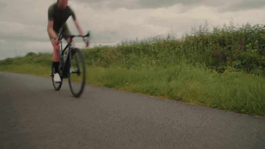 Woman wearing a helmet cycling on a paved road in a rural area