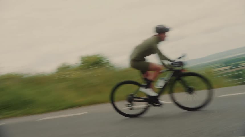 A man is cycling on a road with a helmet on his head