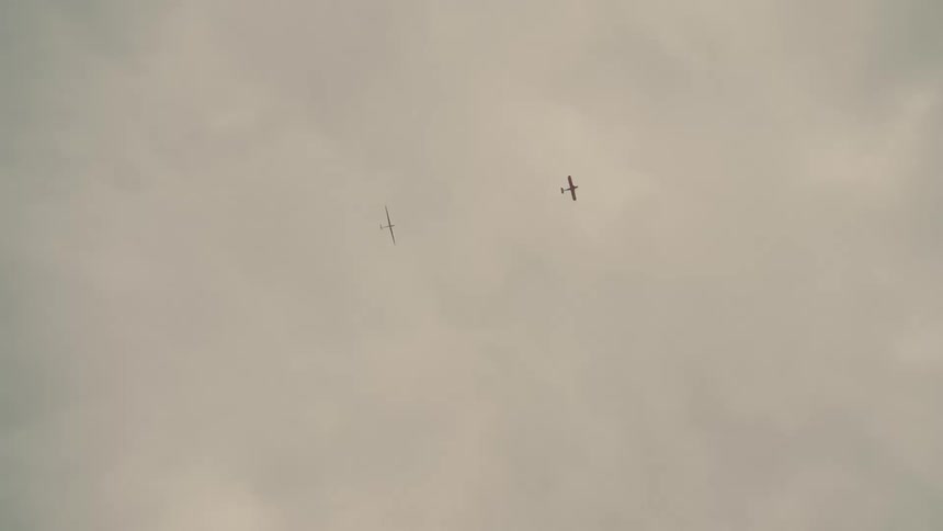 An airplane pulls a glider in the sky