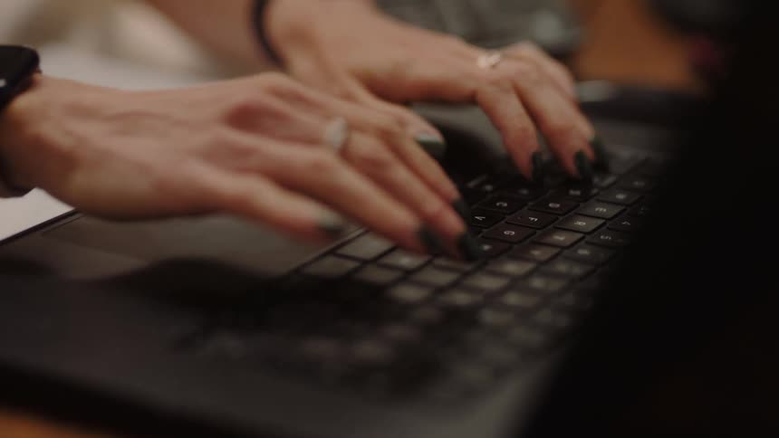 Hands type on a keyboard in a closeup office setting