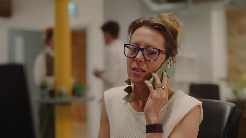 Woman talks on the phone while working in a modern office