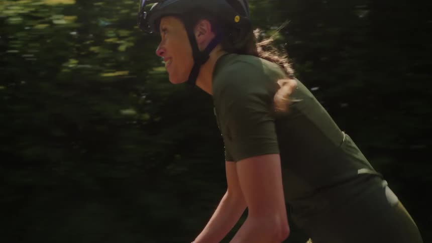 Woman in helmet with happy expression riding bicycle