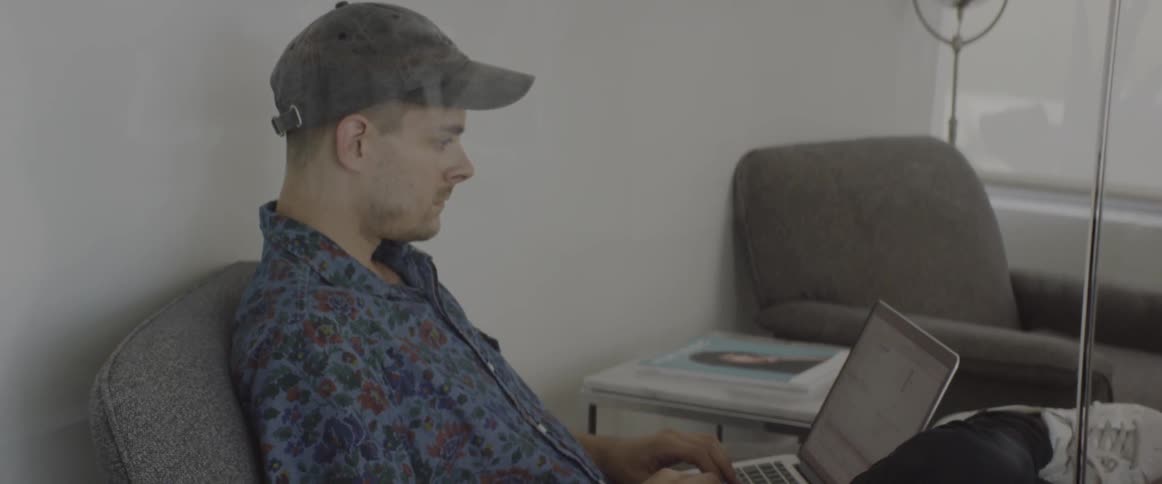 A man is sitting down using a laptop