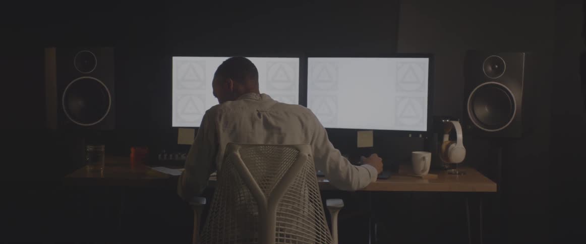 A man sits in front of a computer with two monitors