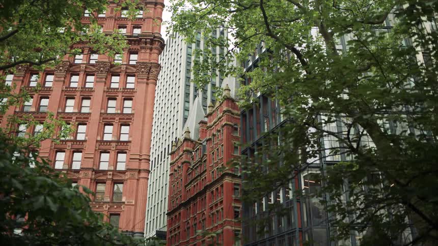 Old red brick buildings contrast with modern glass structures among green trees