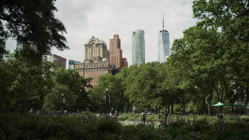 City park with people walking framed by tall skyscrapers in the background