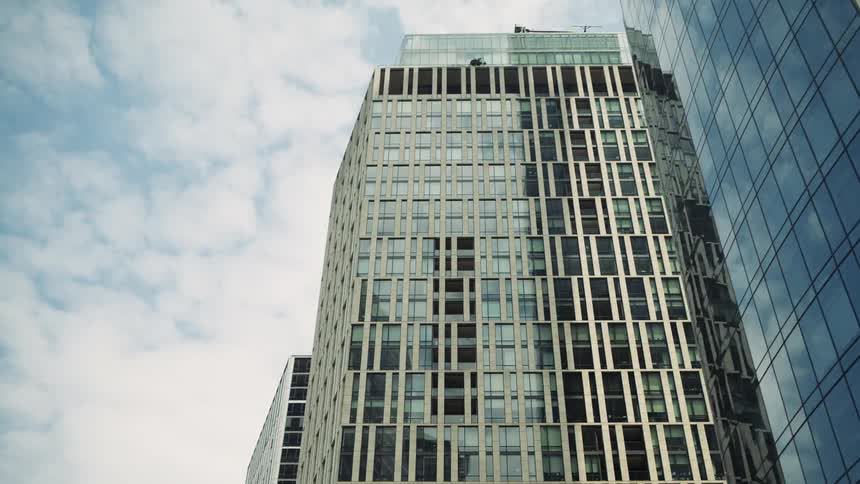 Highrise buildings with rows of windows stand in a city beneath a cloudcovered sky