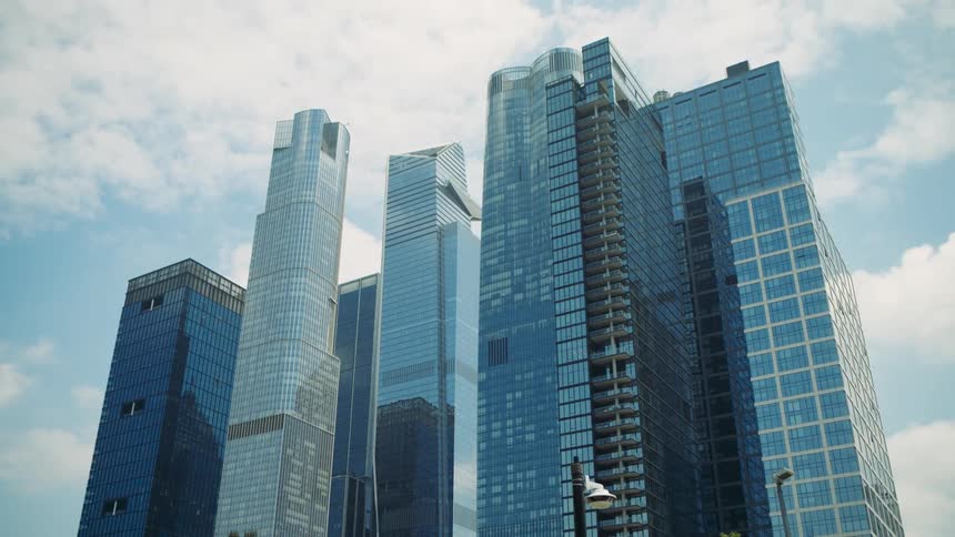 Tall modern skyscrapers with reflective glass facades under a partly cloudy sky