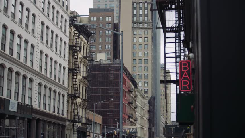 A view of a dense urban environmenta collection of tall buildings under what appears to be an overcast or cloudy skytheres a multistory building with a lightcolored facade and numerous windows characterized by prominent black fire escapes