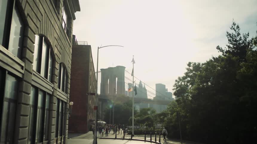 Pedestrians walk on an urban street with a bridge in the background in a metropolis