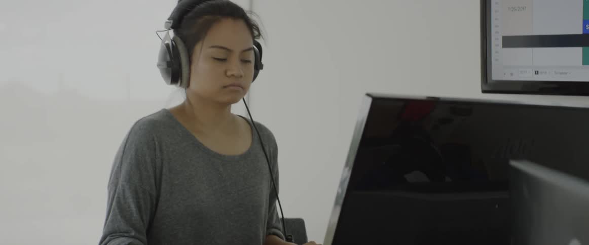 A woman is wearing headphones using a computer