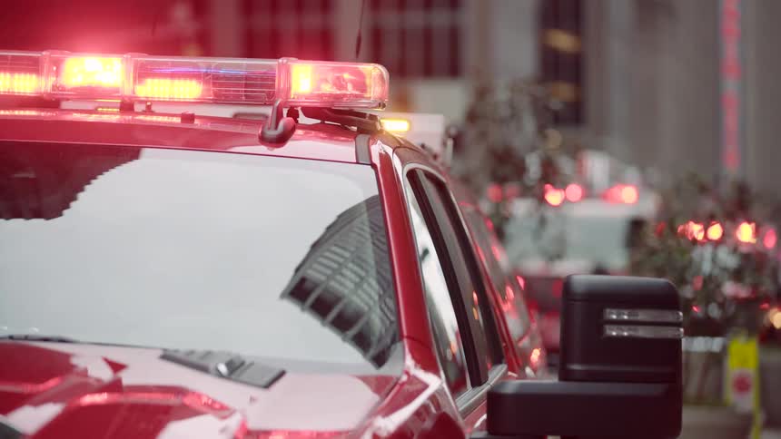 Flashing lights on a fire department vehicle illuminate an active emergency scene on a city street with more first responder vehicles visible in the background
