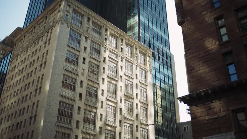 Three highrise buildings with many windows are shown up close in a metropolitan area