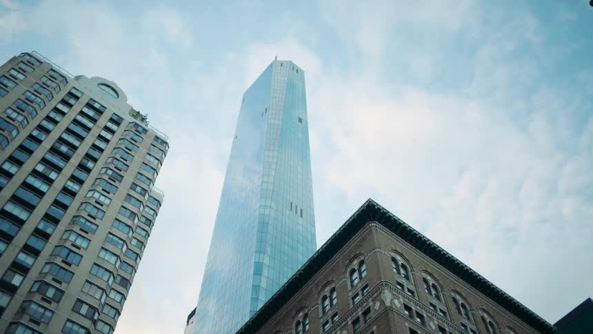 A low angle shot of towering skyscrapers against a blue sky with scattered clouds