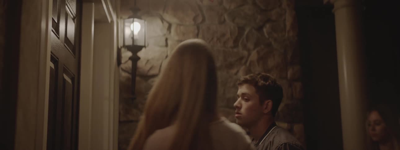 A teenage boy approaches a house door and two girls walk by him and enter