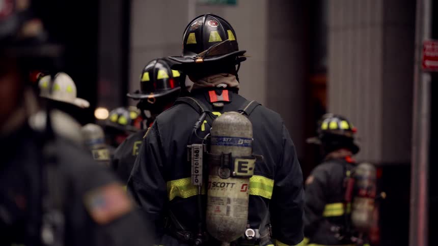 Firefighters in full gear walk through a city street during an emergency response