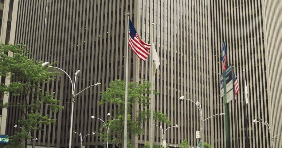 The front of the exxon building features a series of flagpoles and streetlights at midday
