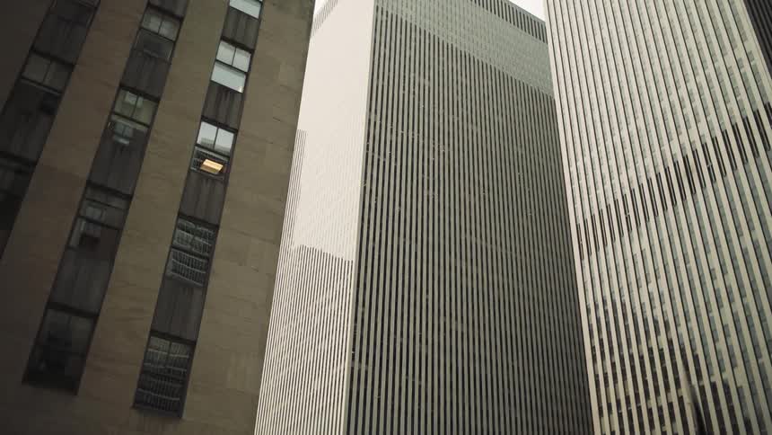 Tall skyscrapers with vertical lines rise closely together in a dense cityscape