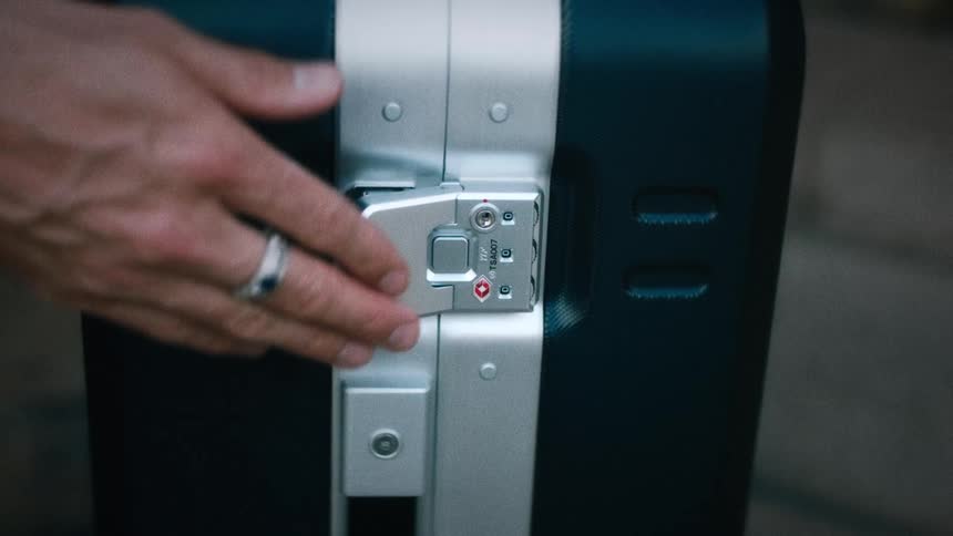 Hand closing the latch of a suitcase