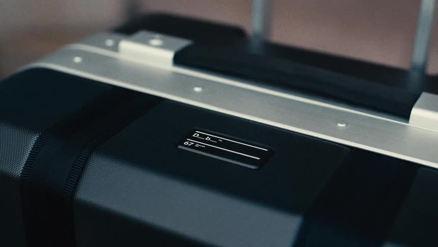 Closeup of a black suitcase with a visible name tag and extended handle