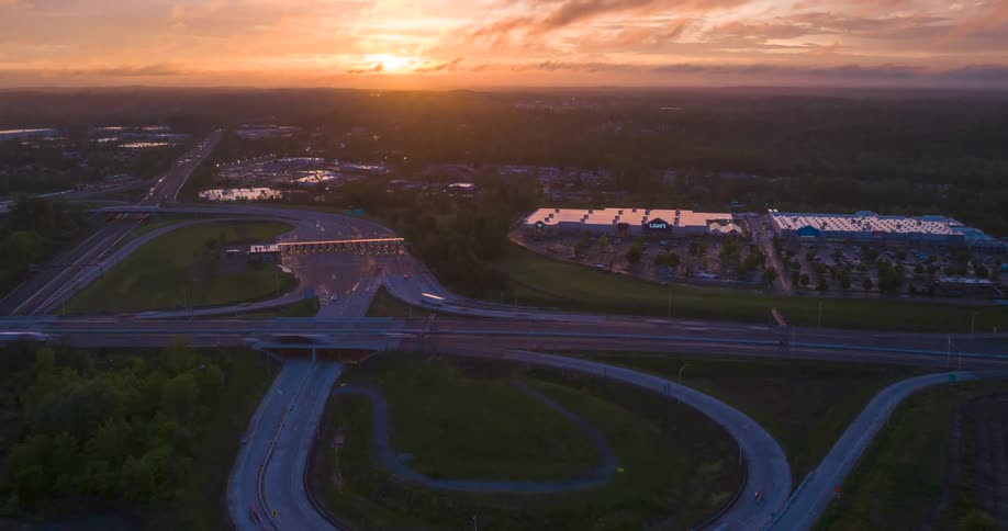 Aerial view of a highway interchange at sunset near a suburban commercial area