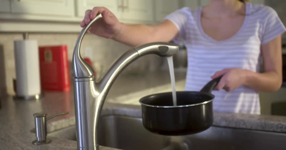 A woman fills a pan with water