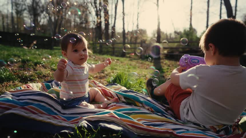 Two children sitting on a colorful carpet playing and having fun with soap bubbles