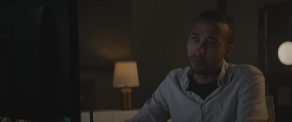 A man sitting at a desk looking at a computer