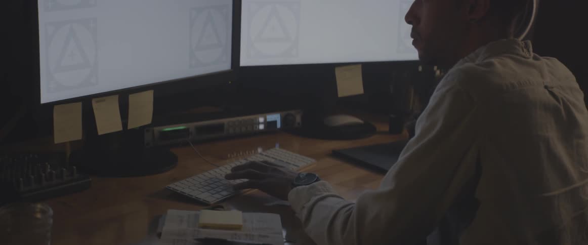 Man sitting at desk in front of computer monitors and typing on keyboard
