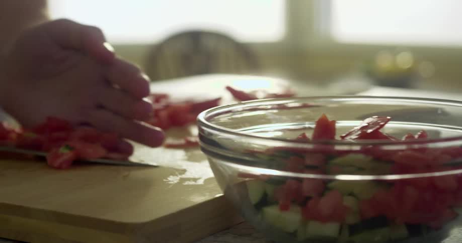 A person is cutting up food into a bowl