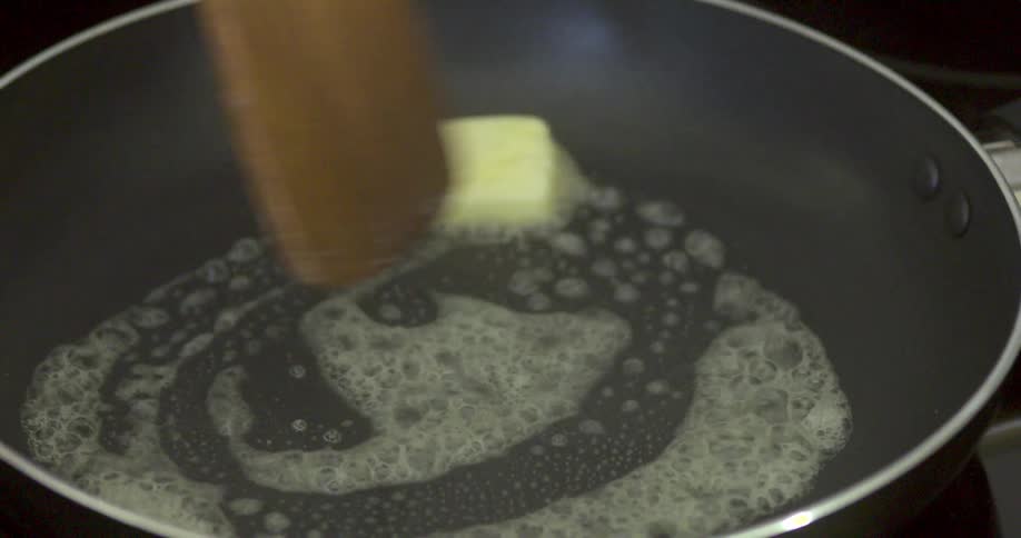 Butter is being stirred in a hot pan