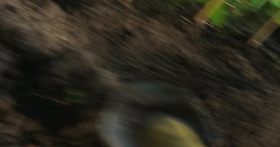 A closeup shows a shovel scooping soil with motion blur around it