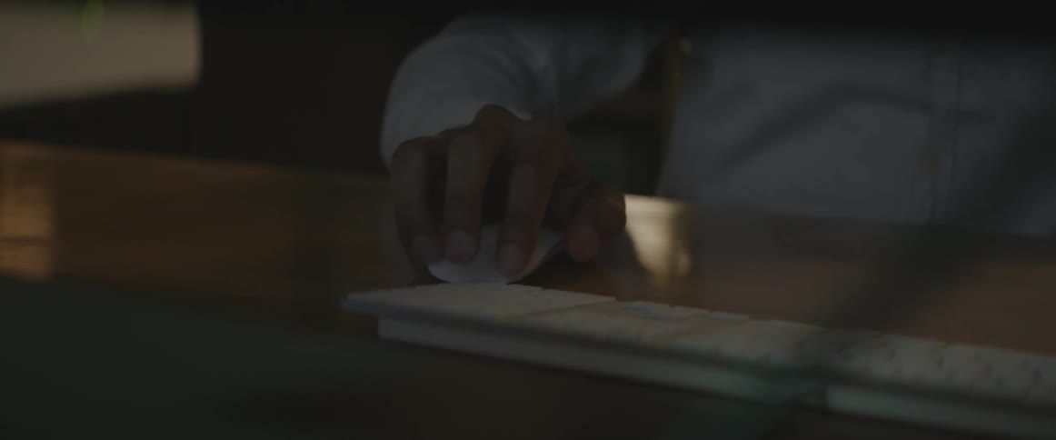 A man types at a computer and uses the mouse