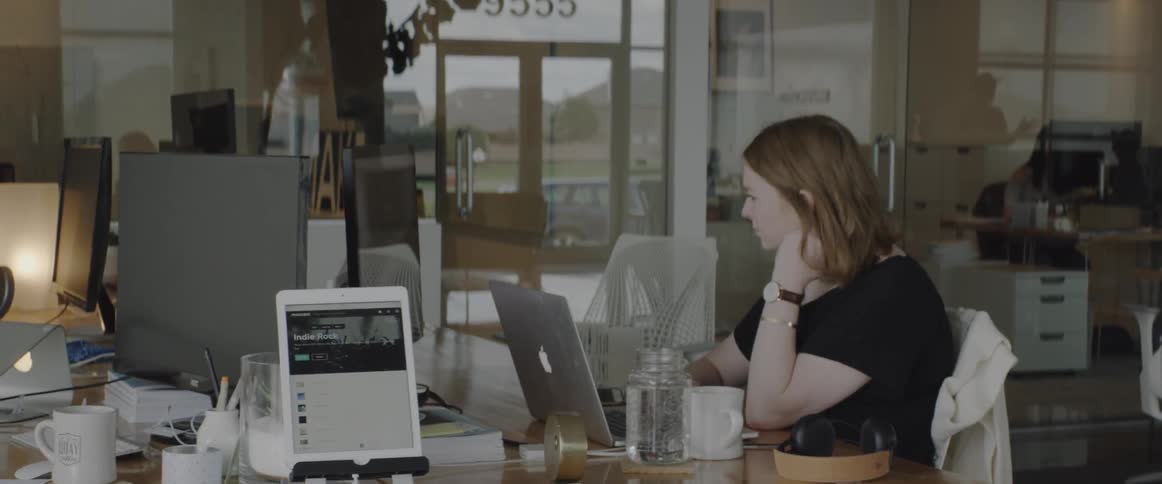 A woman sits at a desk and works on a laptop