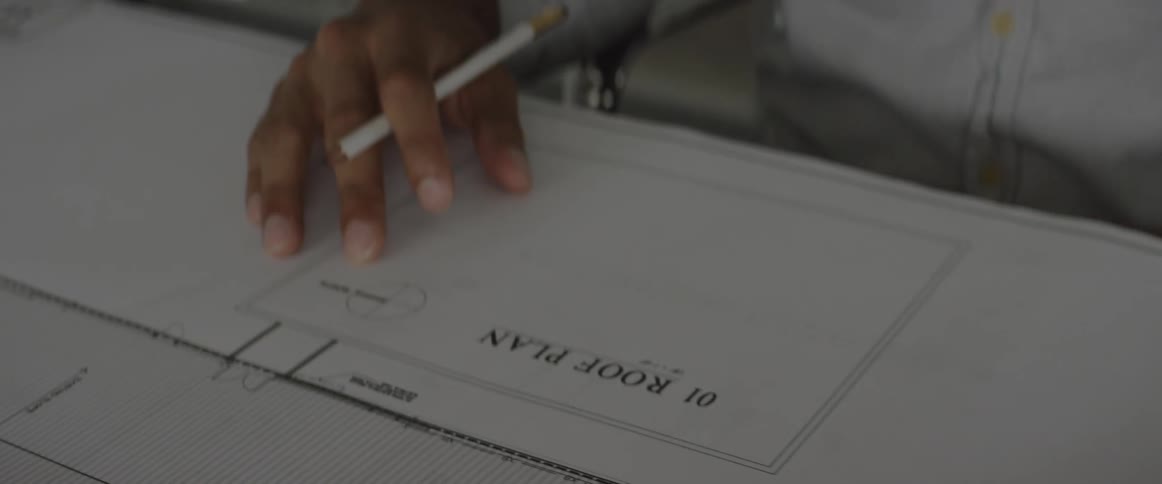 A person flipping through blueprints in an office setting