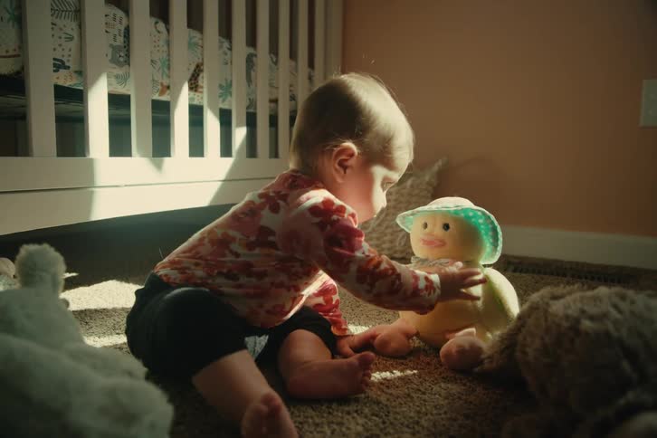 Baby sitting on the carpet playing with a teddy bear