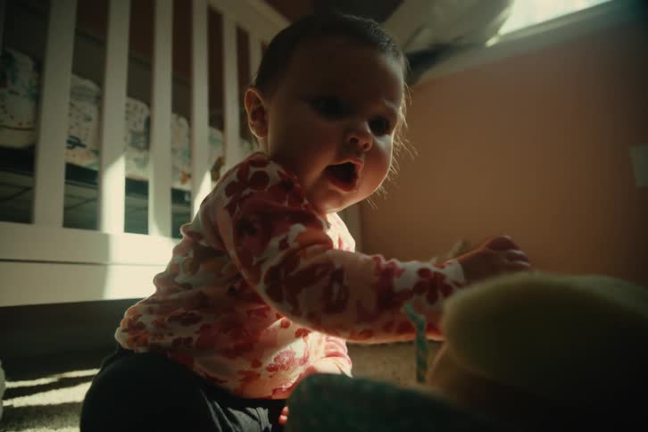 Close up of a baby playing with a stuffed toy while sitting on the floor in a room during daytime