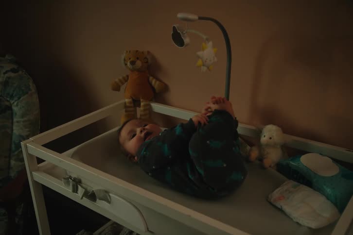 The baby is kicking while laying on the changing table