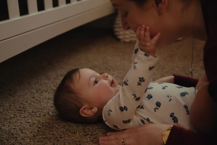 A mother talks to and kisses her baby