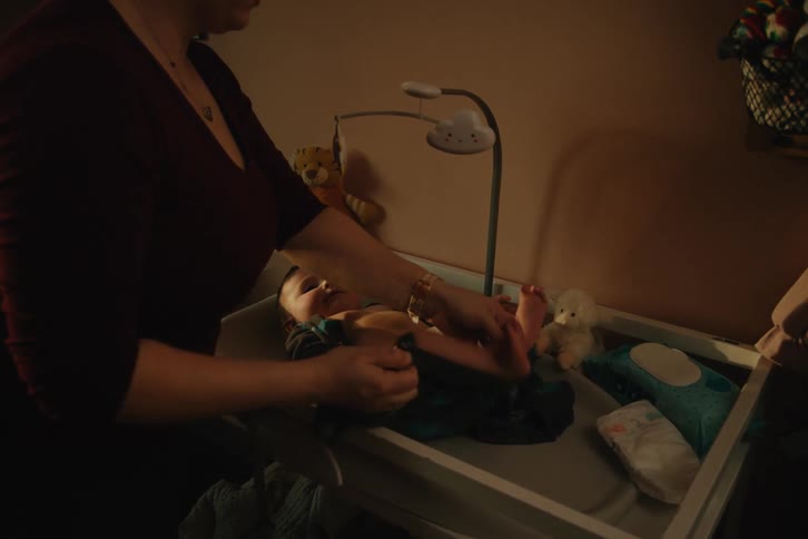 A mother changes her sons diapers
