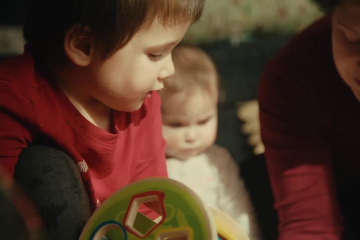 A mother talks with her children while they play with toys