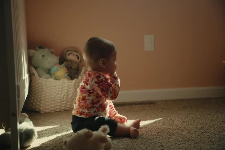 Baby sitting in a room with her hand in her mouth