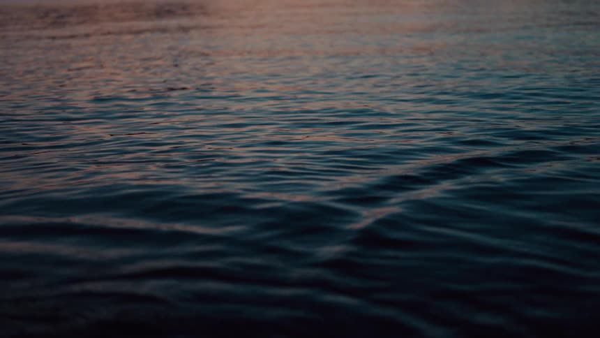 The sun is setting in the horizon above the ocean water