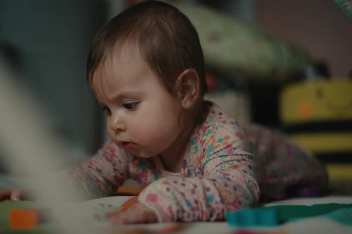 An active baby tries to put its toys into its mouth while on its belly