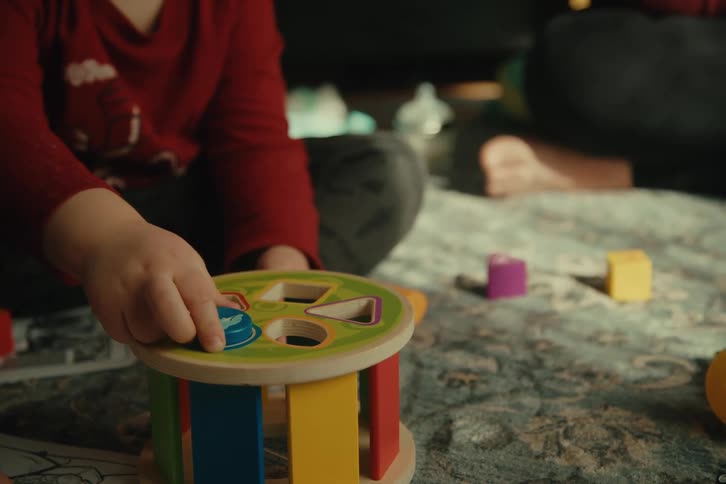 Hand of a small child playing with toys on a carpet
