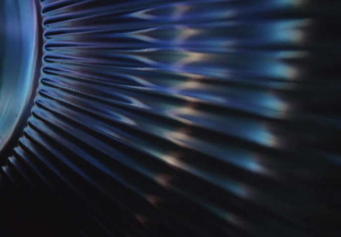 A closeup of a metallic ribbed industrial or artistic surface with blue lighting