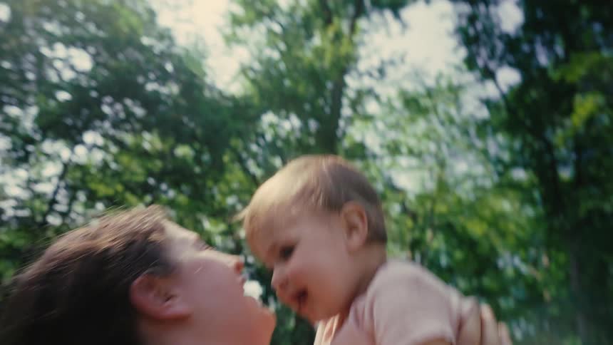 Mother lifts her daughter up and kisses her