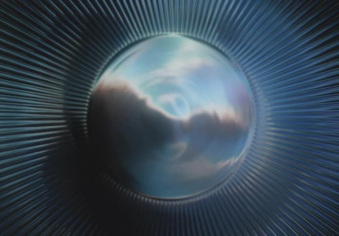 A metallic circular structure reflects light in a pattern resembling an abstract turbine or lens